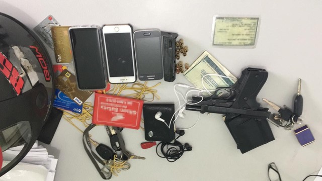 Arma, celulares, relógio, documentos, entre outros materiais apreendidos com os suspeitos